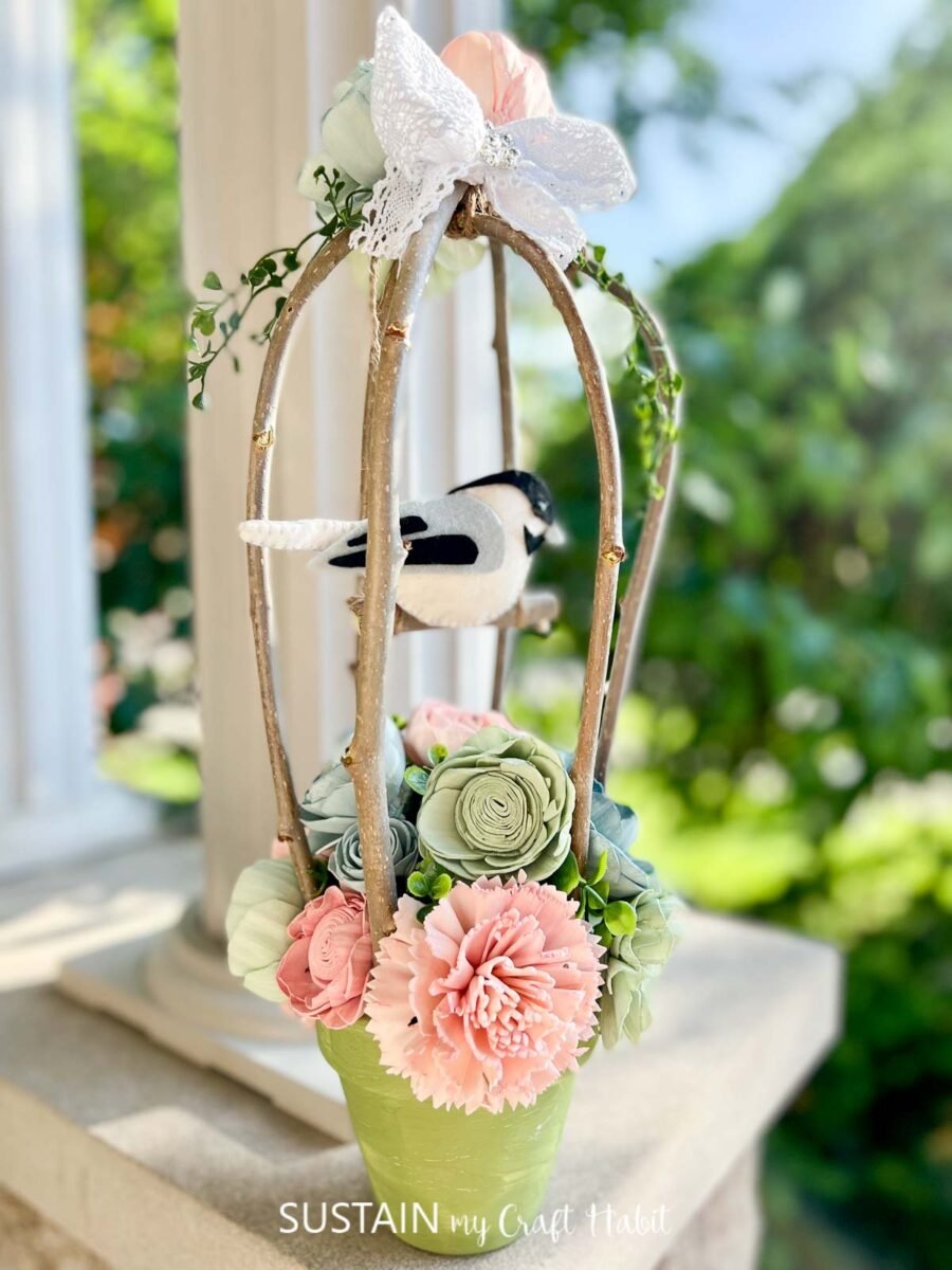 Decorative birdcage made with twigs, wood flowers and a felt bird.