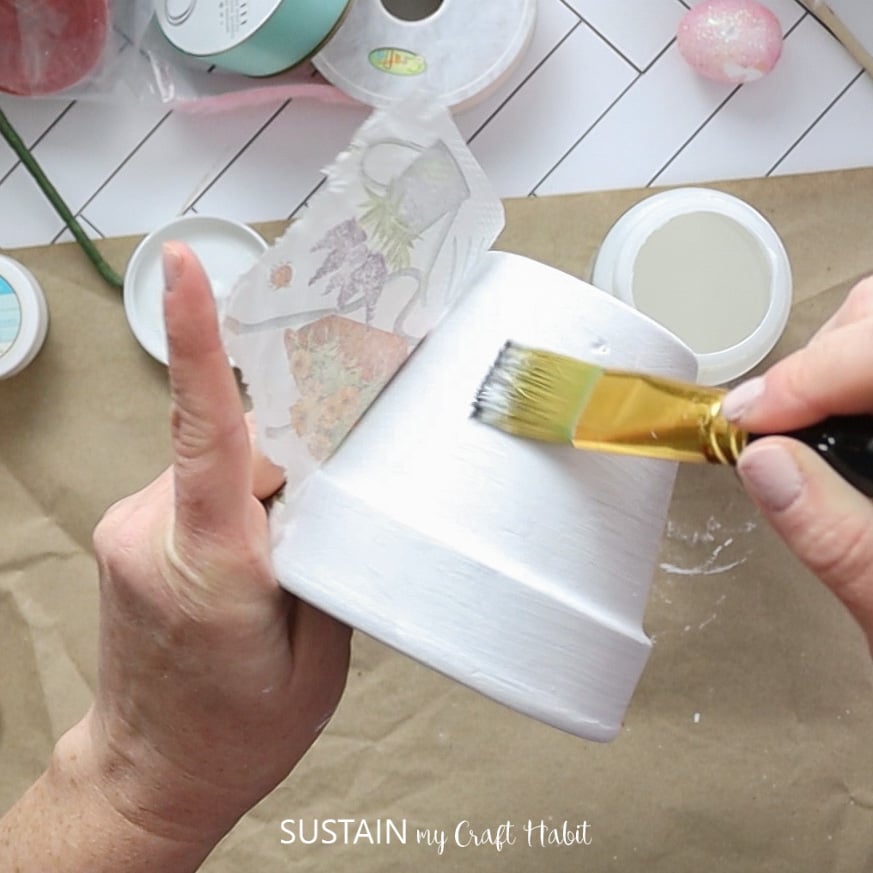 Adding glue onto the painted clay pot.