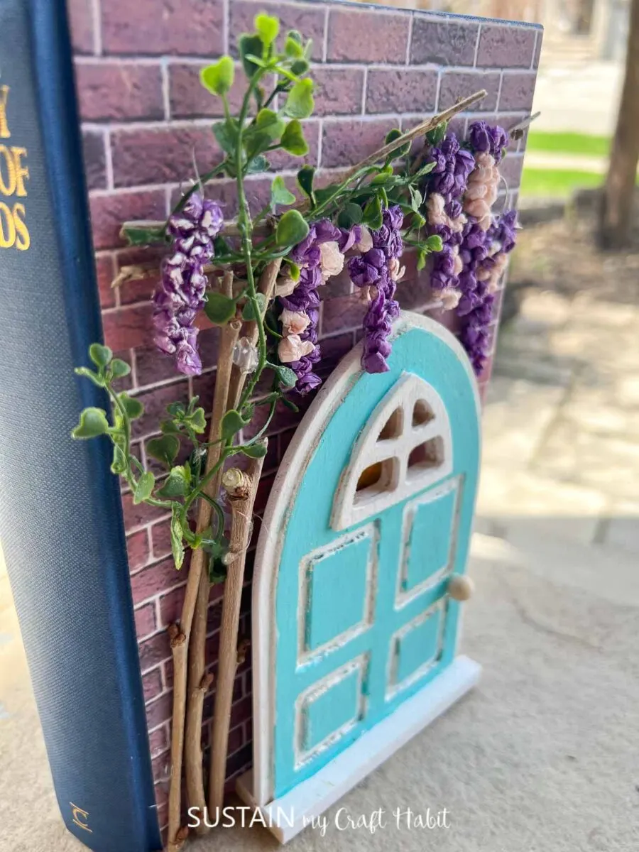 Upcycled book craft with decorative paper, painted wood door, twigs and flowers.