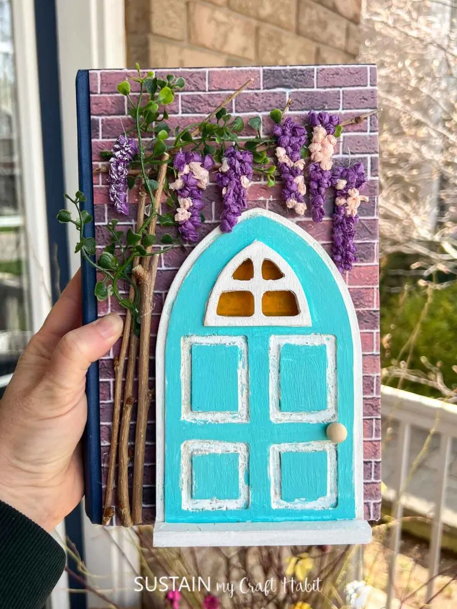 Upcycled book craft with decorative paper, painted wood door, twigs and flowers.