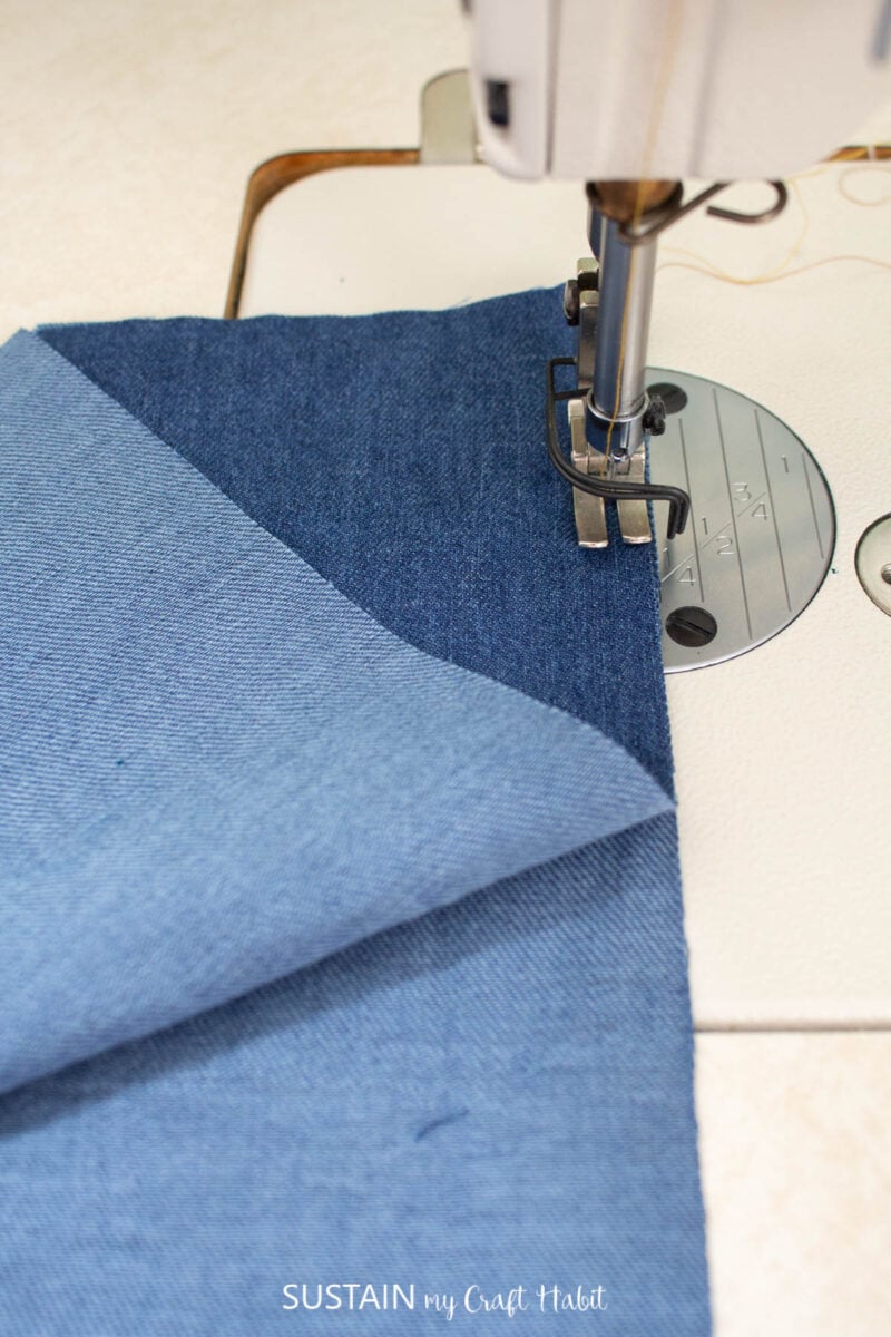 Sewing machine sewing a stitch into a piece of blue fabric.