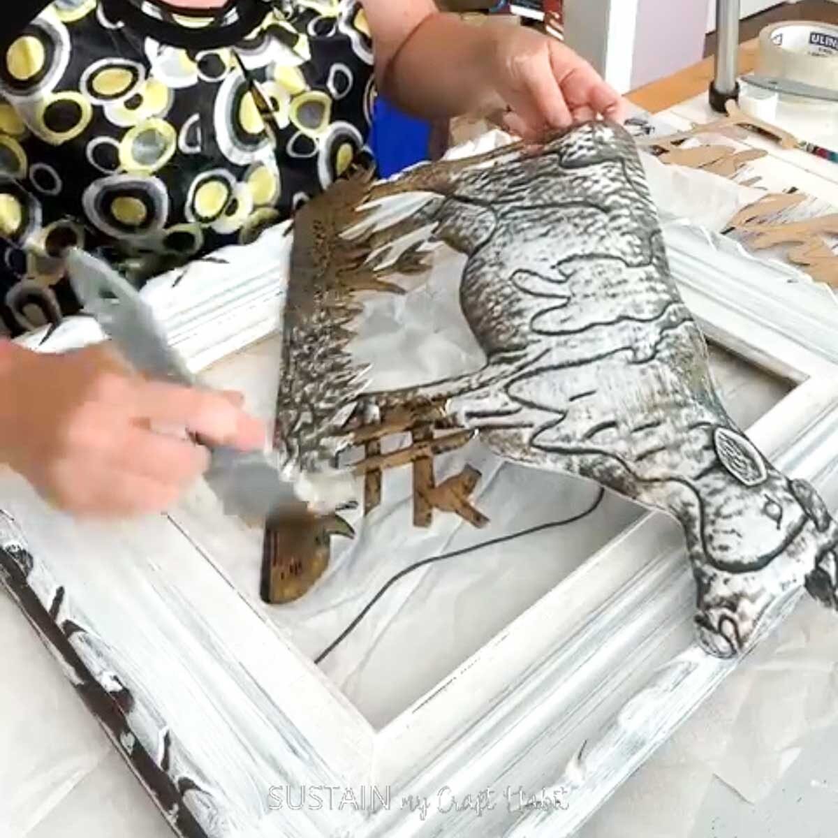 Painting a metal cow with white paint.