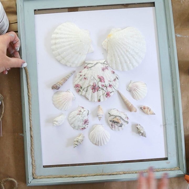 Arranging seashells on a painted frame.