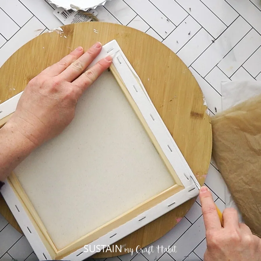 Using a utility knife to remove the canvas from the frame.