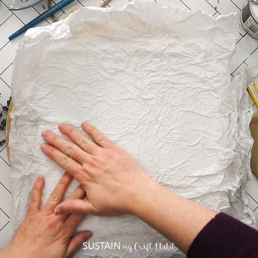 Gluing crinkled tissue paper onto a canvas.