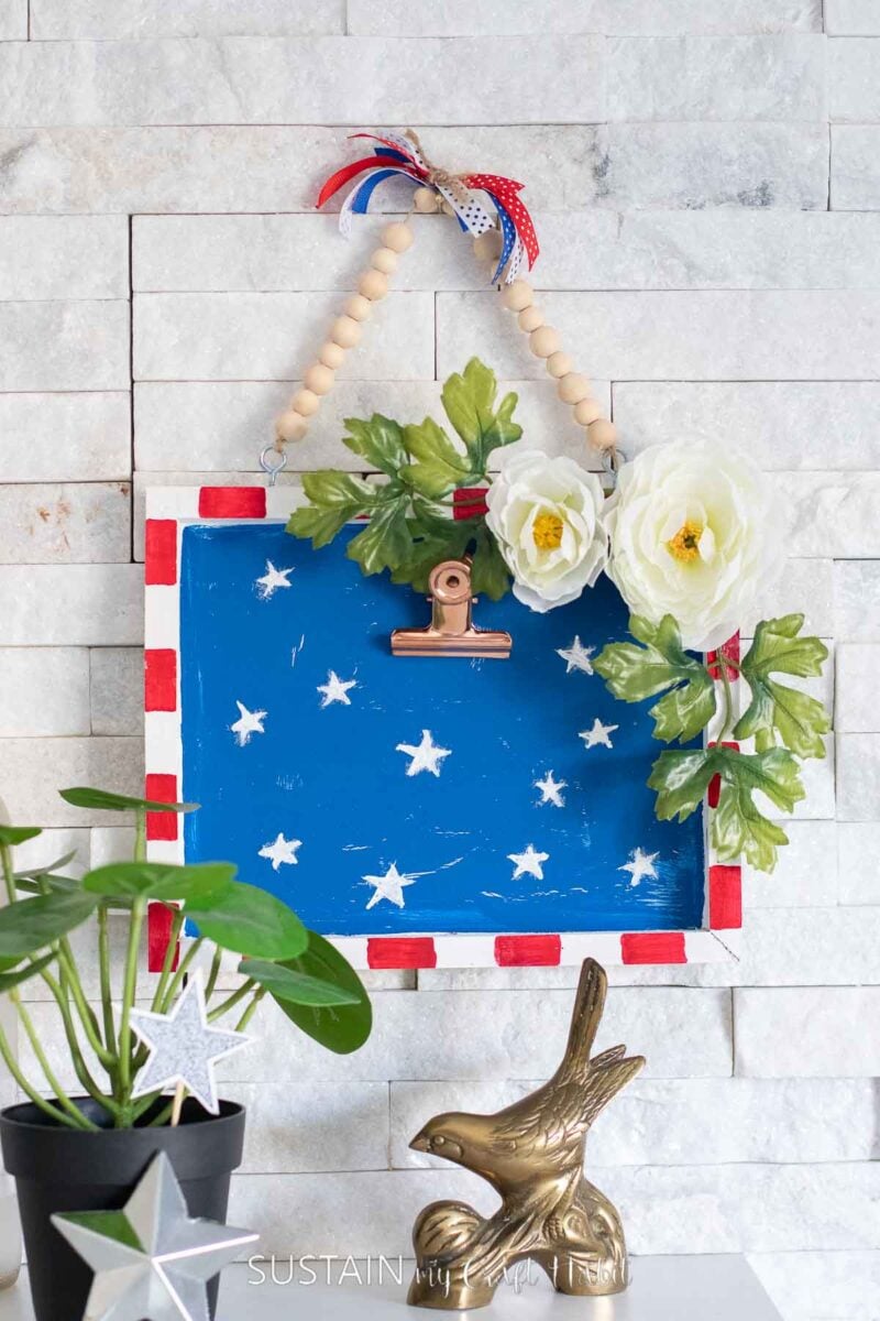 Fourth of July decorated wood canvas painted red, white and blue and embellished with flowers and stars.