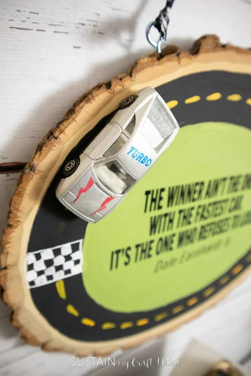 Close up of toy race car glued onto a wood slice race track.