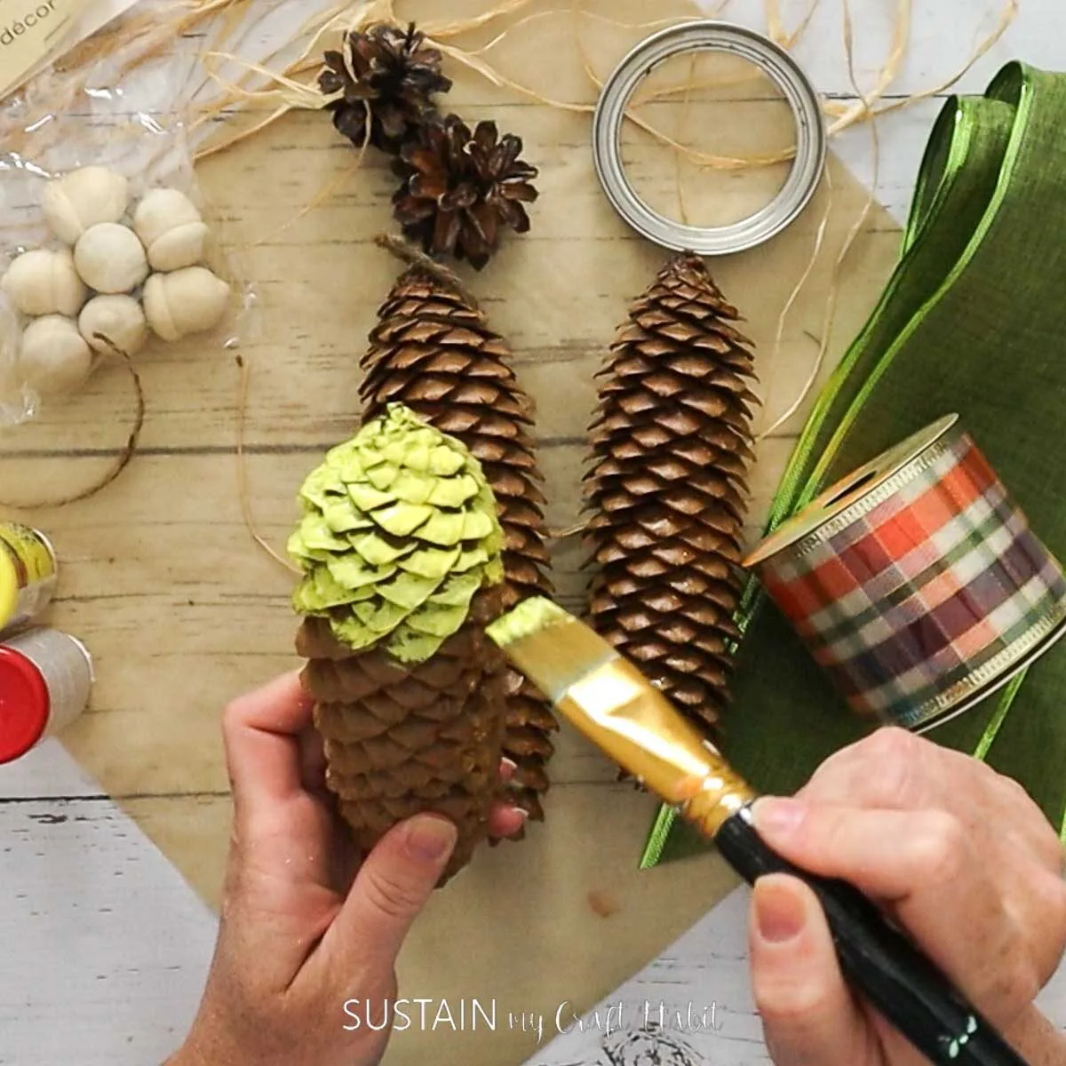 Painting the top half of a pinecone yellow.