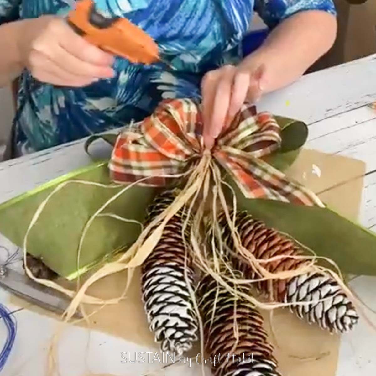 Hot gluing ribbon onto a pine cone.