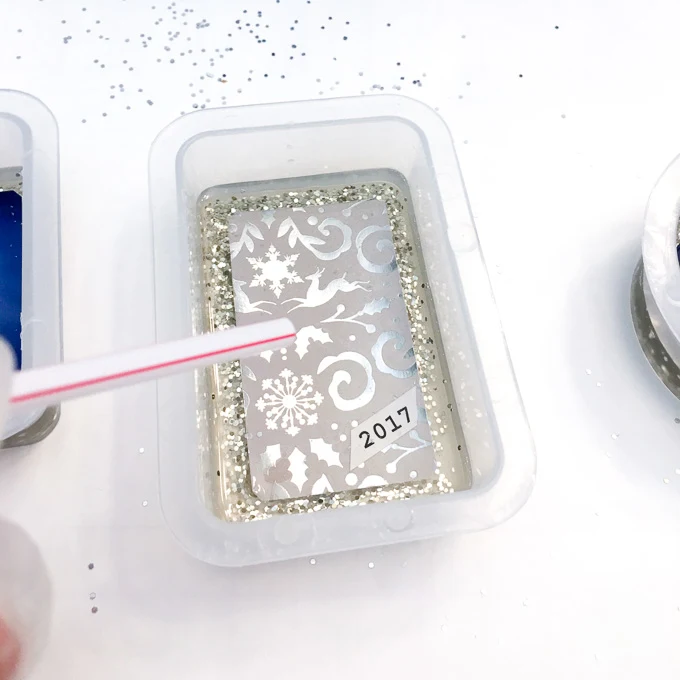 Using a straw to blow off any bubbles in the resin.