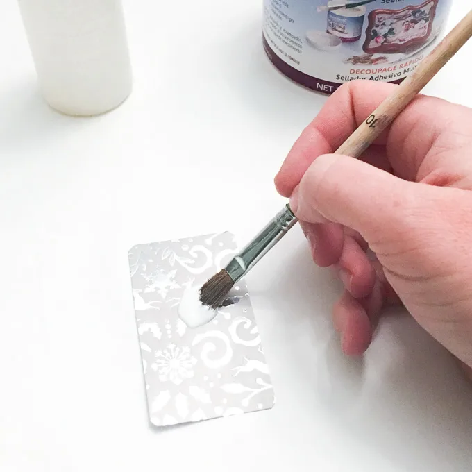 Using a paint brush to seal decorative paper.