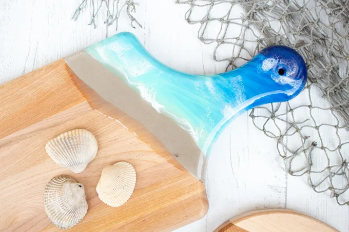 Resin cutting board with beachy themed handle.