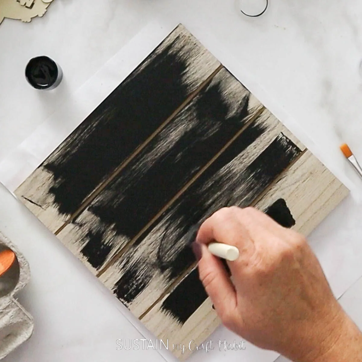 Painting a wood slate with black paint.