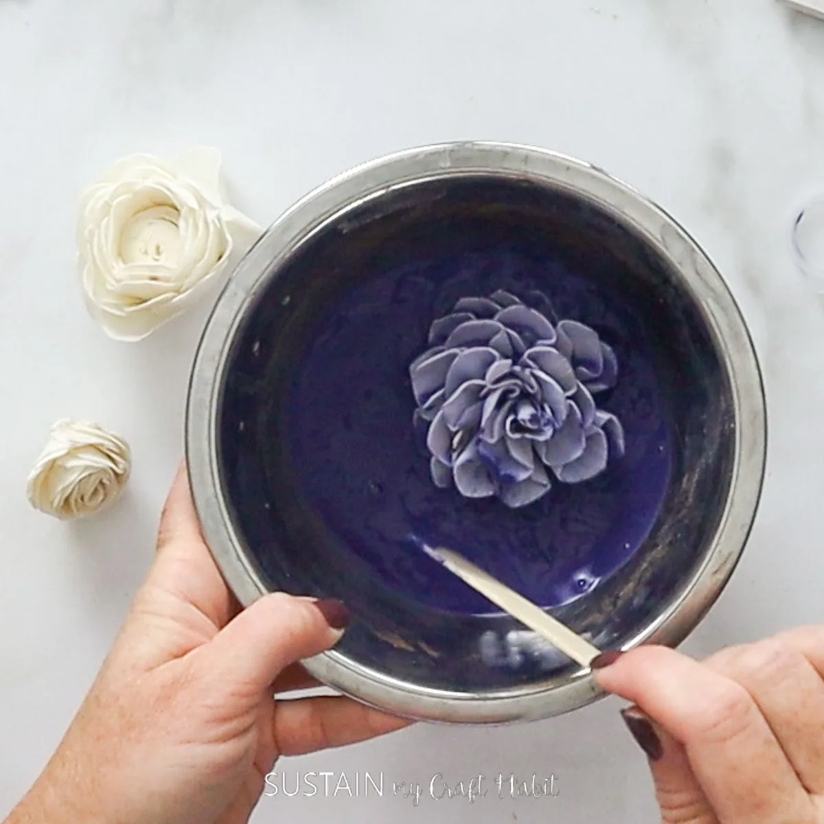 Dipping a Sola Wood flower into the dye mixture.