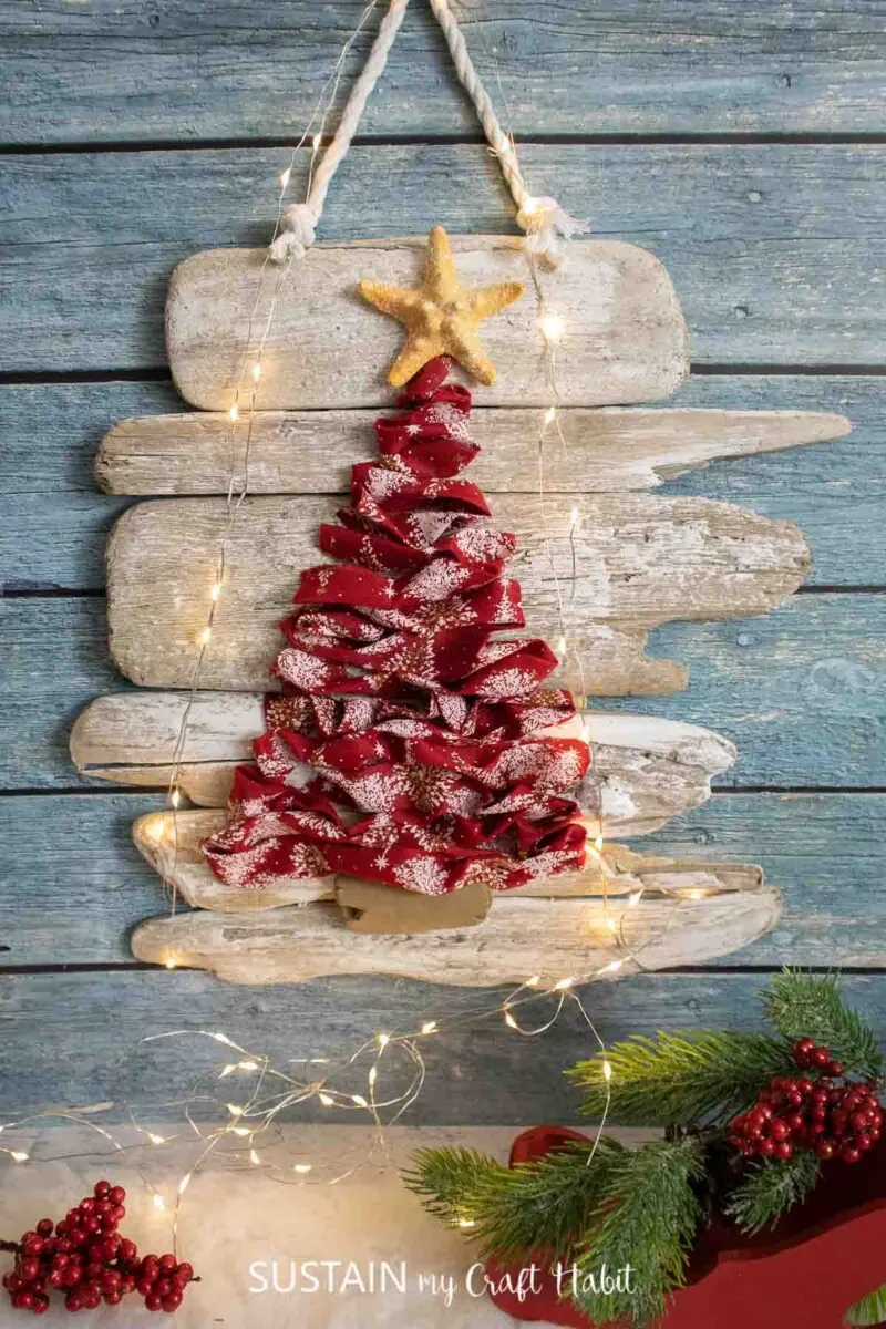 Ribbon Christmas tree on a driftwood hung on a wall.