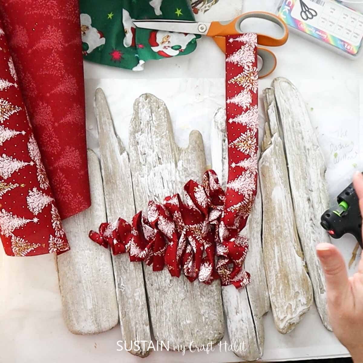 Hot gluing strips of ribbon to form a Christmas tree.