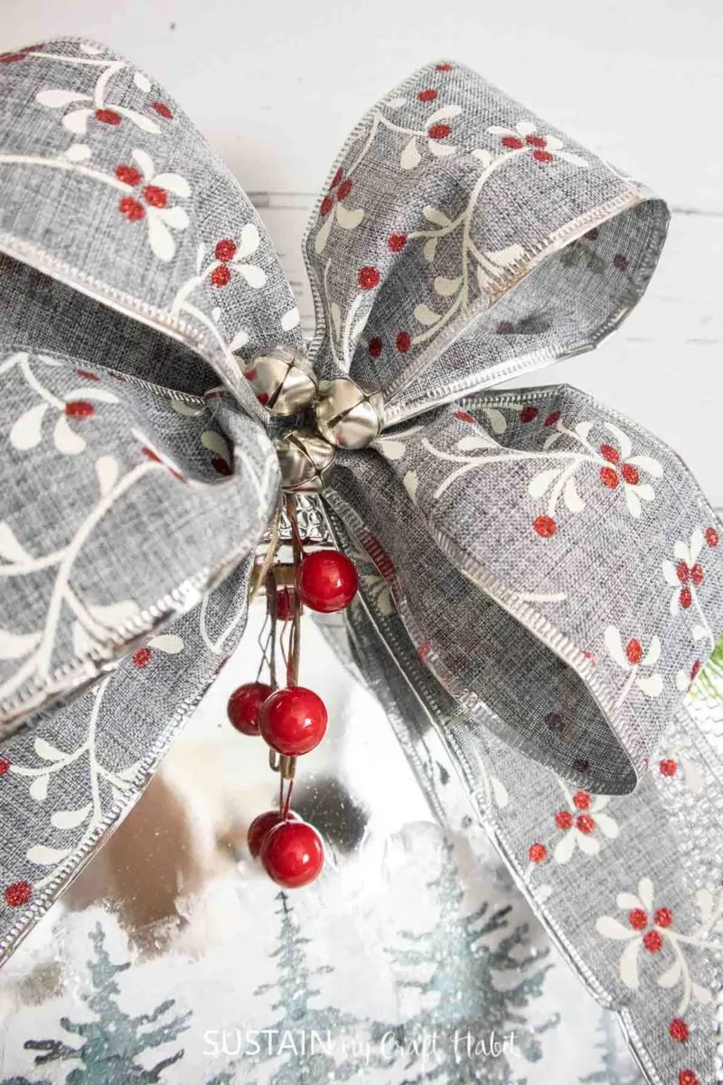 Close up of silver bow with bells and berries.