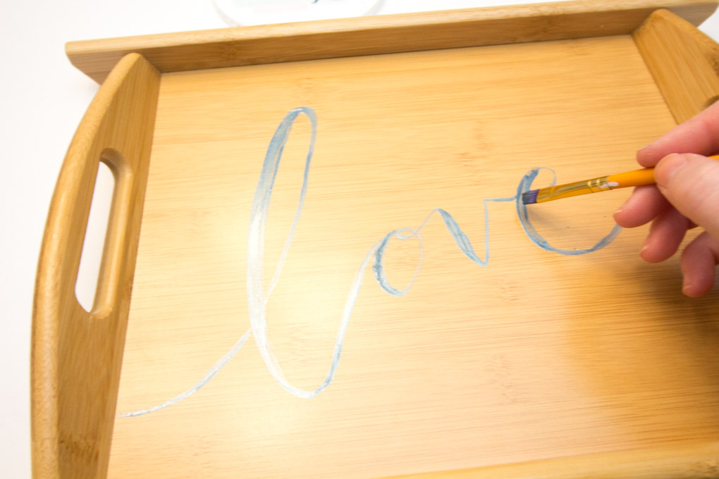 Painting the word "love" onto a wood tray.