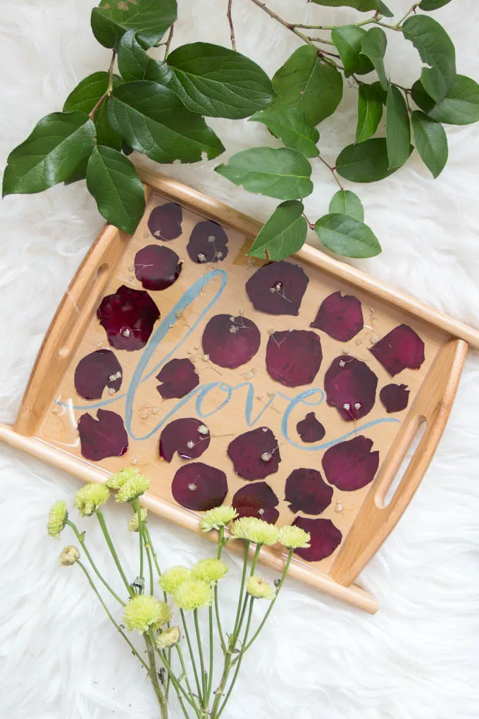 Dried rose petal serving tray next to flowers and leaves.