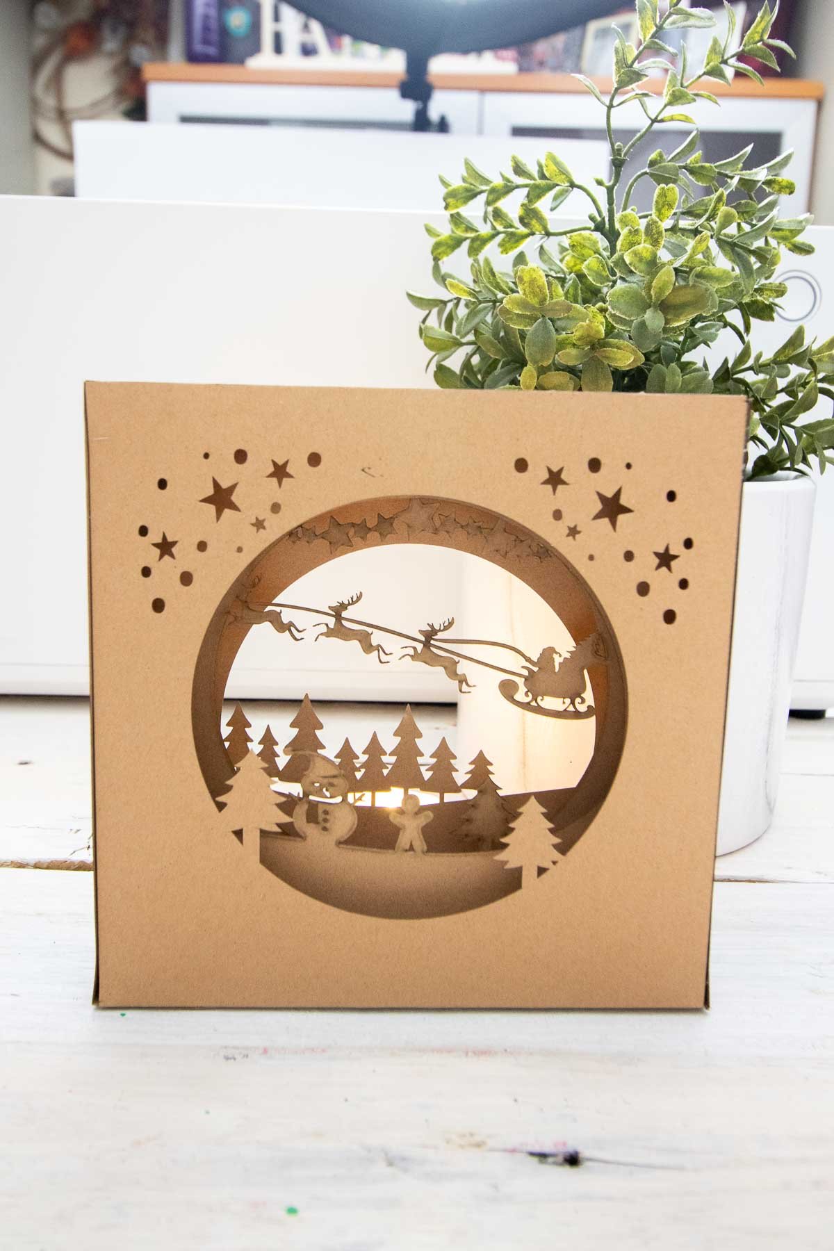 A 4-layered winter scene cut into brown kraft paper to create a nightlight display.