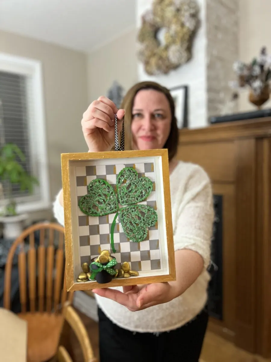 Woman holding a Saint Patrick's day framed craft with a wood hearts shamrock and gold nuggets.