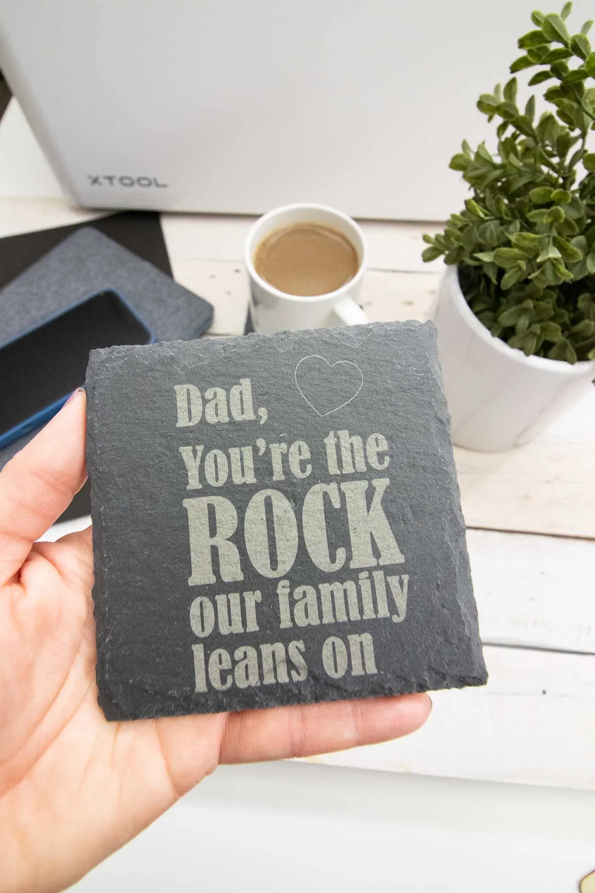 Hand holding an engraved slate coaster as an example of a Father's Day gift idea.