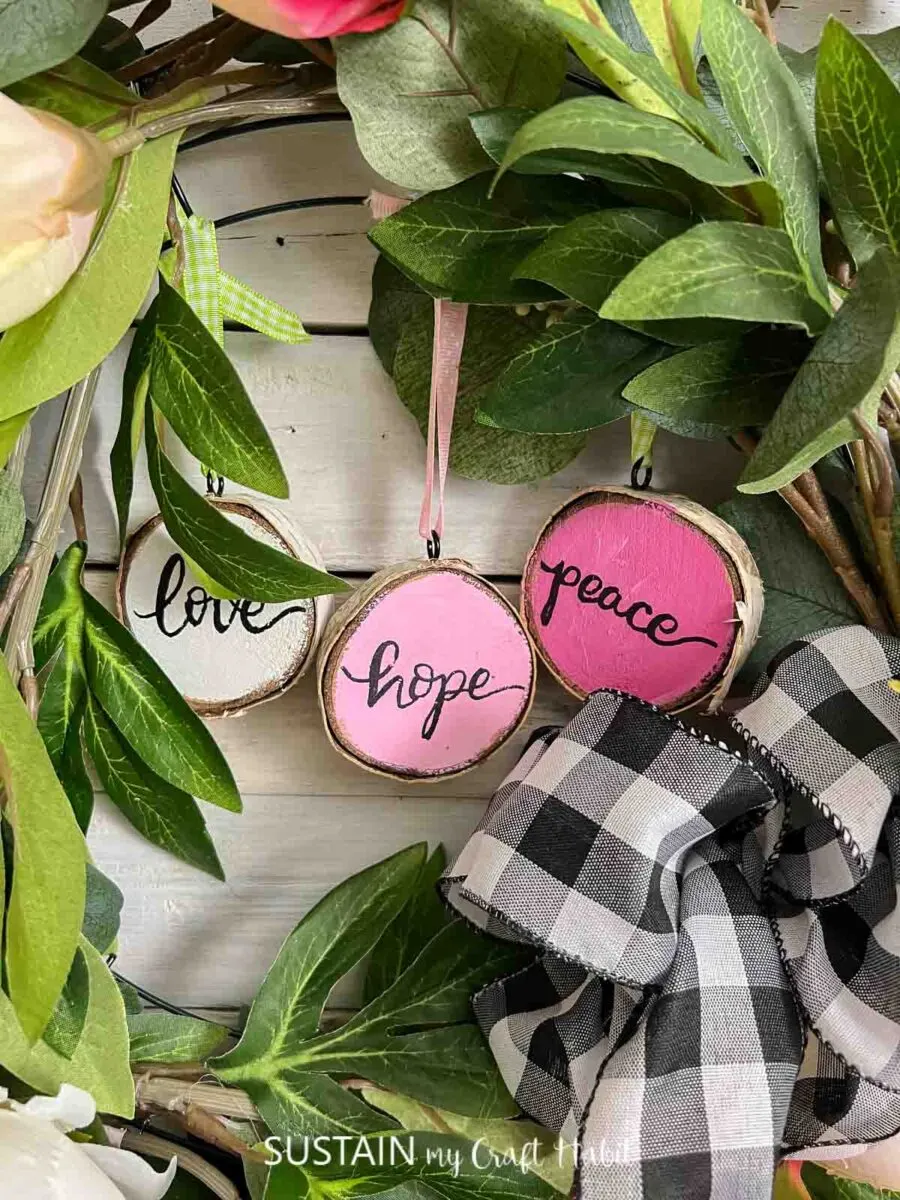 Close up of painted wood slices hanging from a spring wreath.