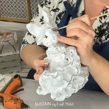 Using a paintbrush to paint details onto a ceramic bunny.