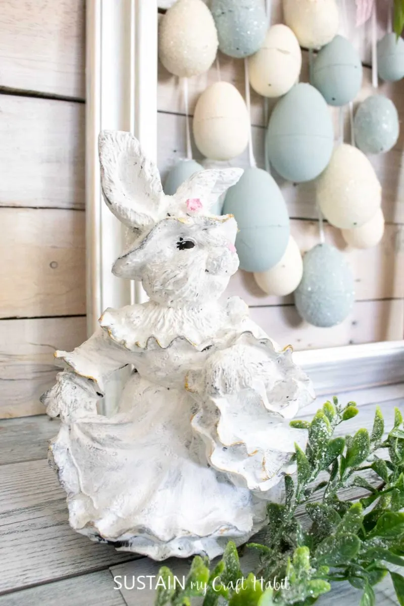 Painted ceramic bunny next to decorated Easter eggs.