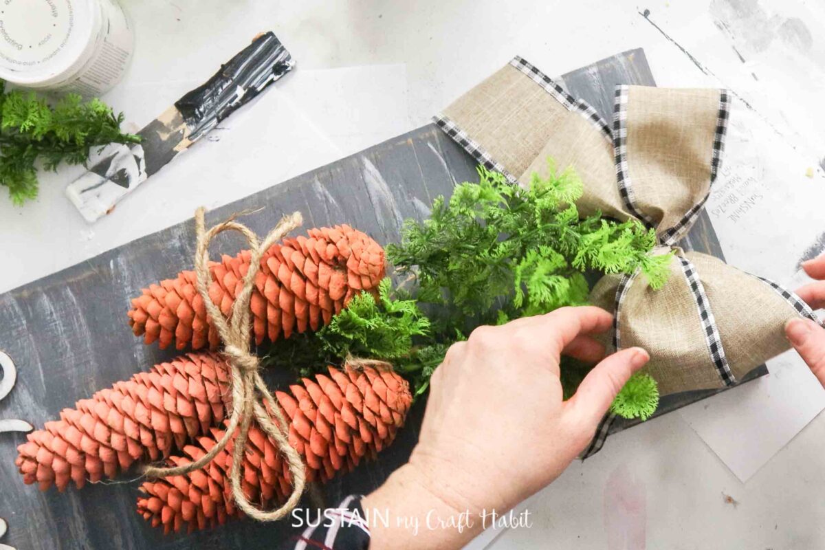 Attaching a ribbon to the pinecone carrot sign.