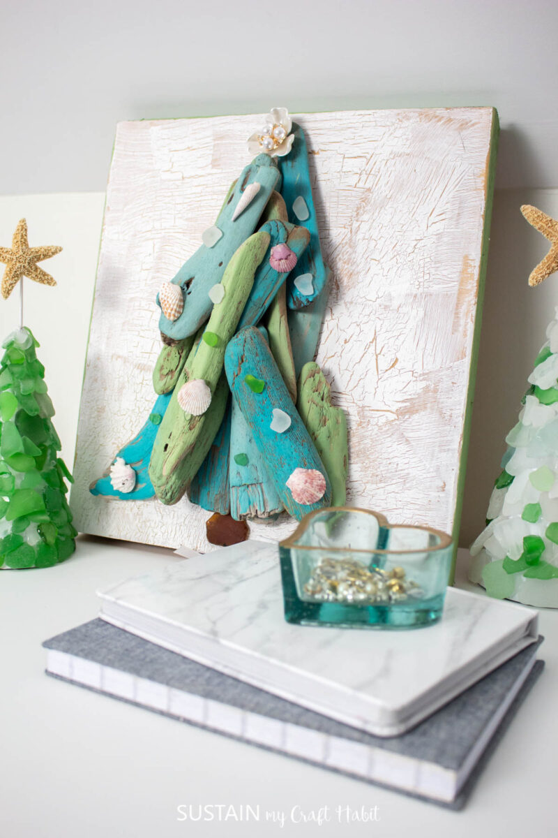 Driftwood tree art on a wood board decorated with sea glass and sea shells. 