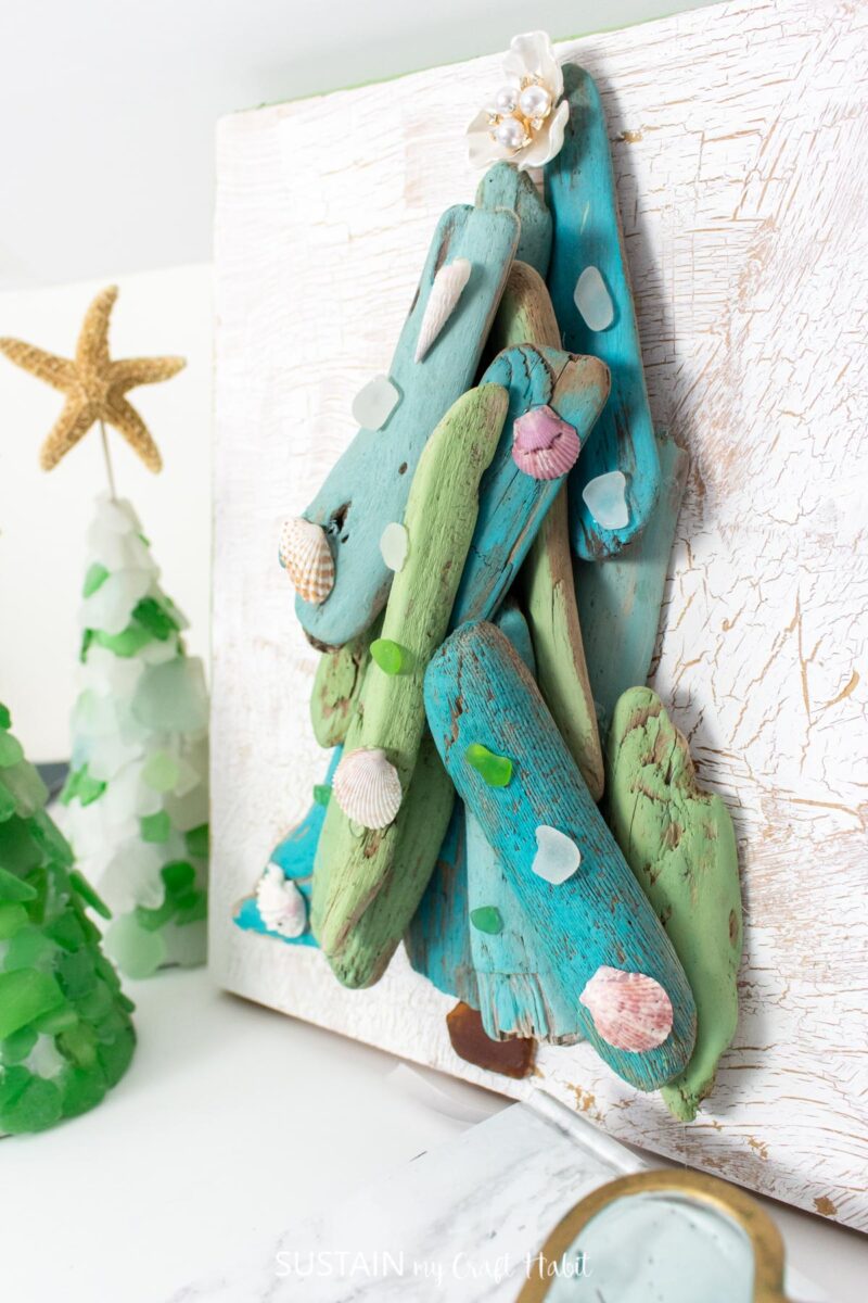 Driftwood tree art on a wood board decorated with sea glass and sea shells. 