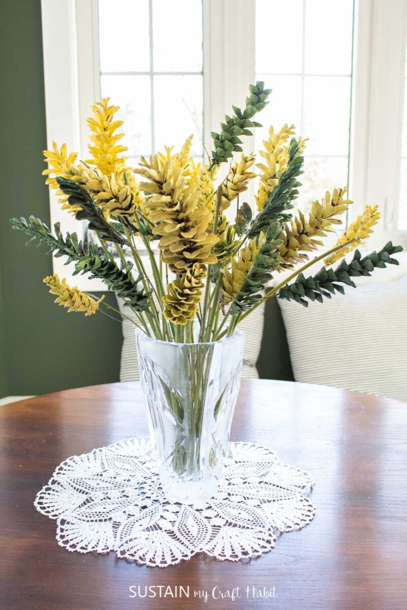 Forsythia bouquet made from painted pine cones and placed in a clear vase.