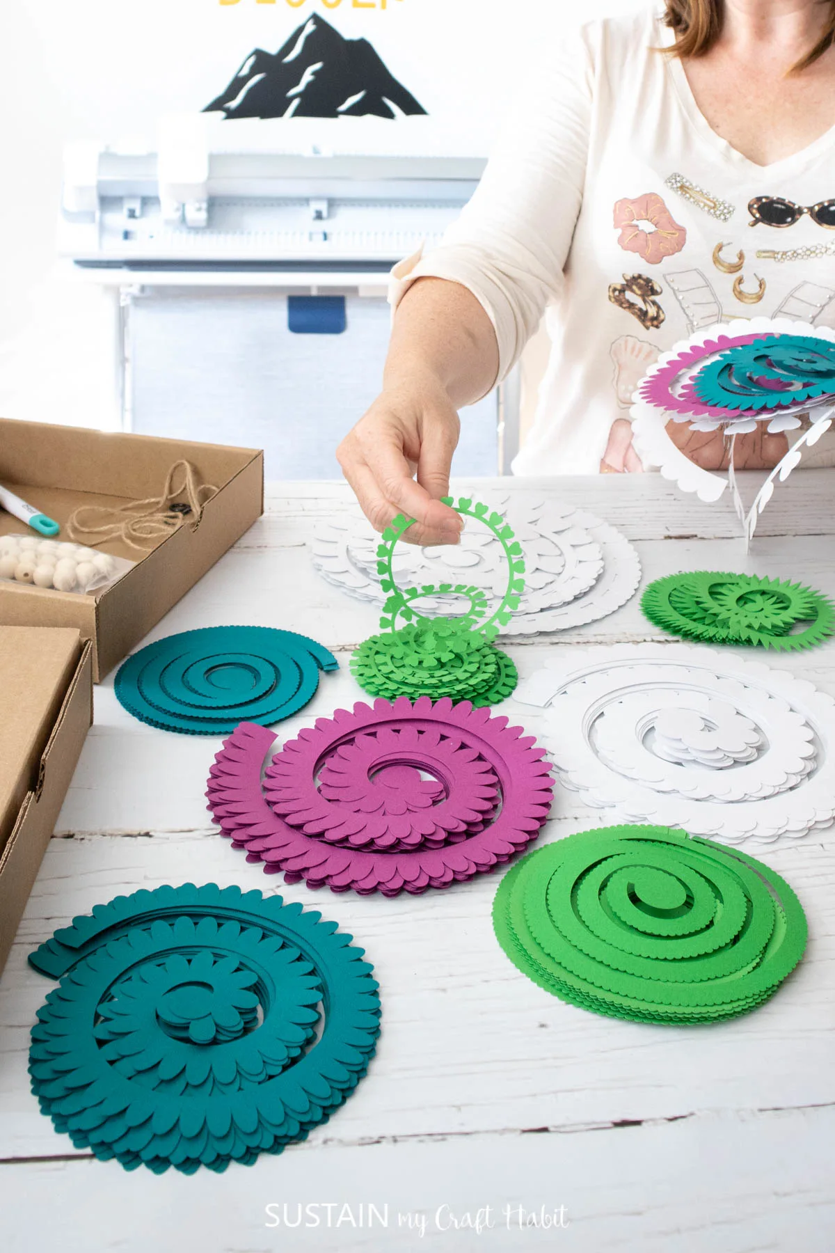 woman holding a pile of spiral cut papers in front of cricut venture