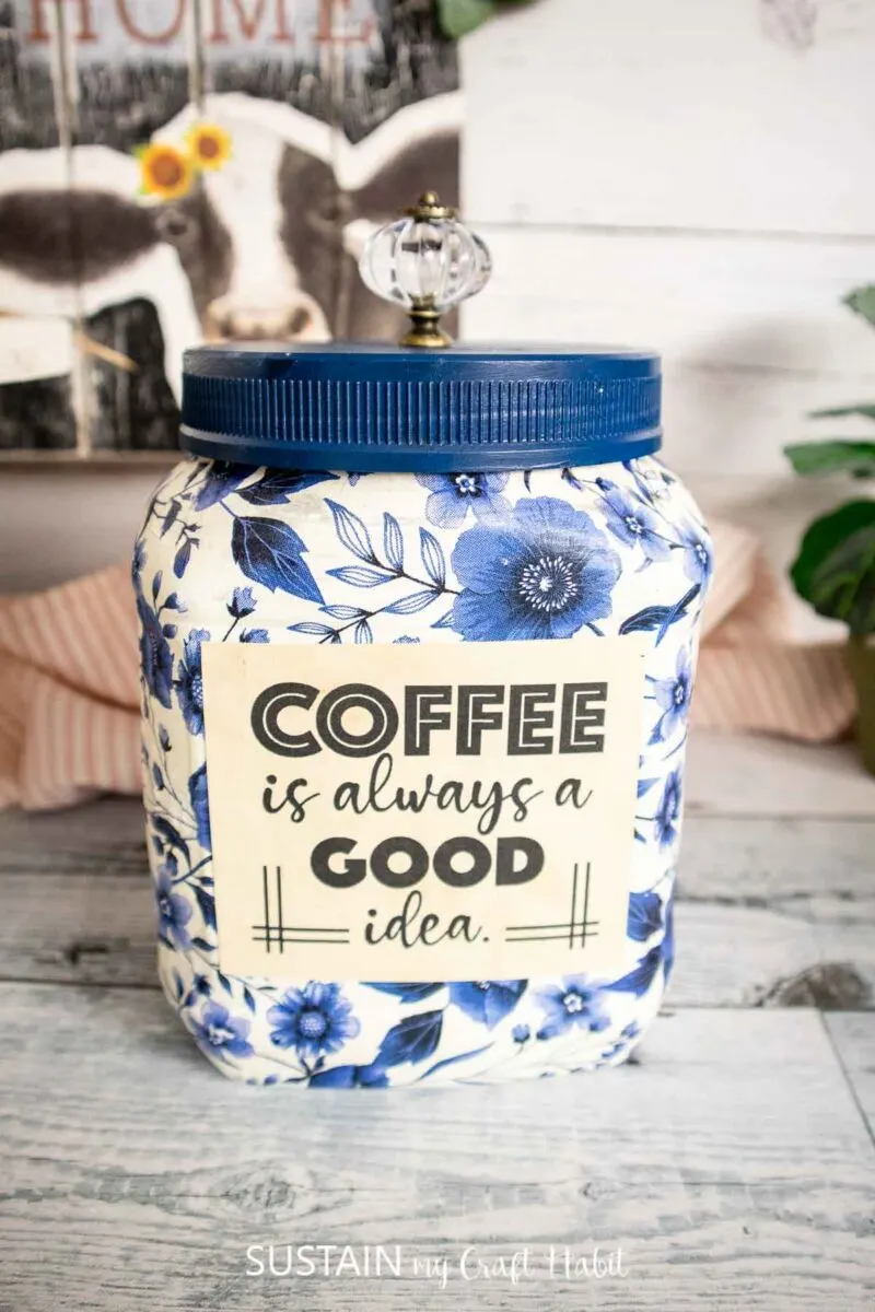 Upcycled coffee canister craft decorated with decoupage, paint and a decorative knob.