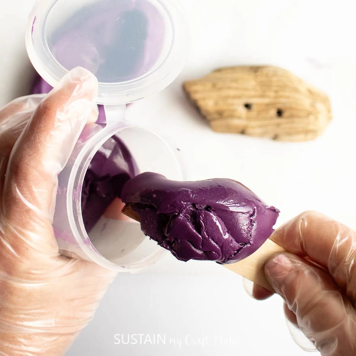 Scooping out purple silicone putty from a container.