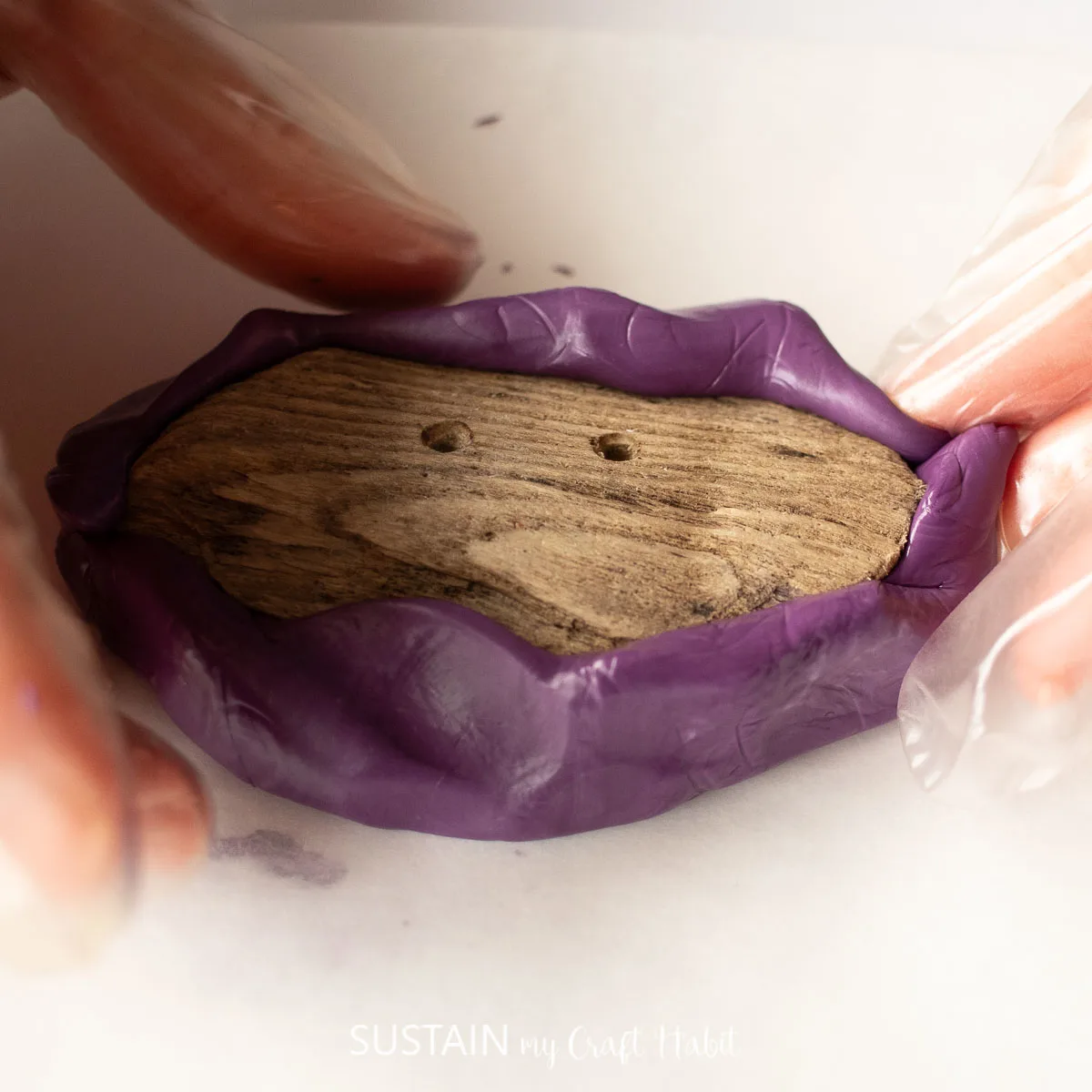 Wrapping silicone putty around the edges of a driftwood button.