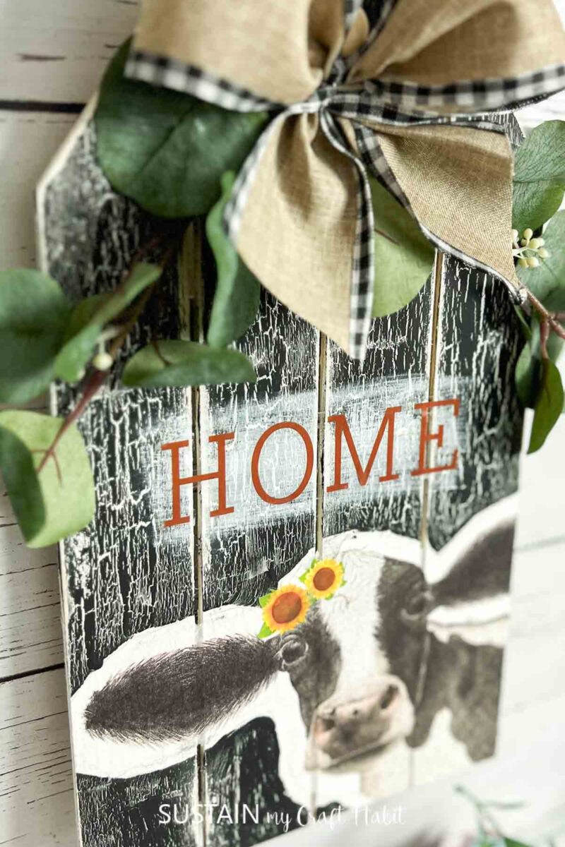 Farmhouse kitchen cow sign decorated with ribbon and greenery
