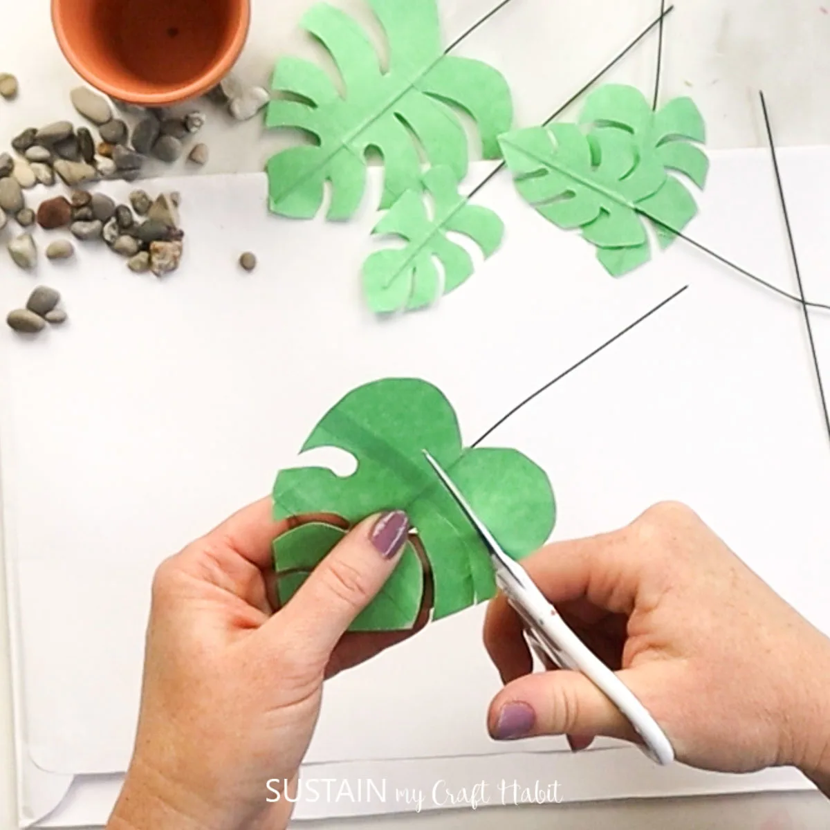 Cutting masking tape to form a leaf shape.
