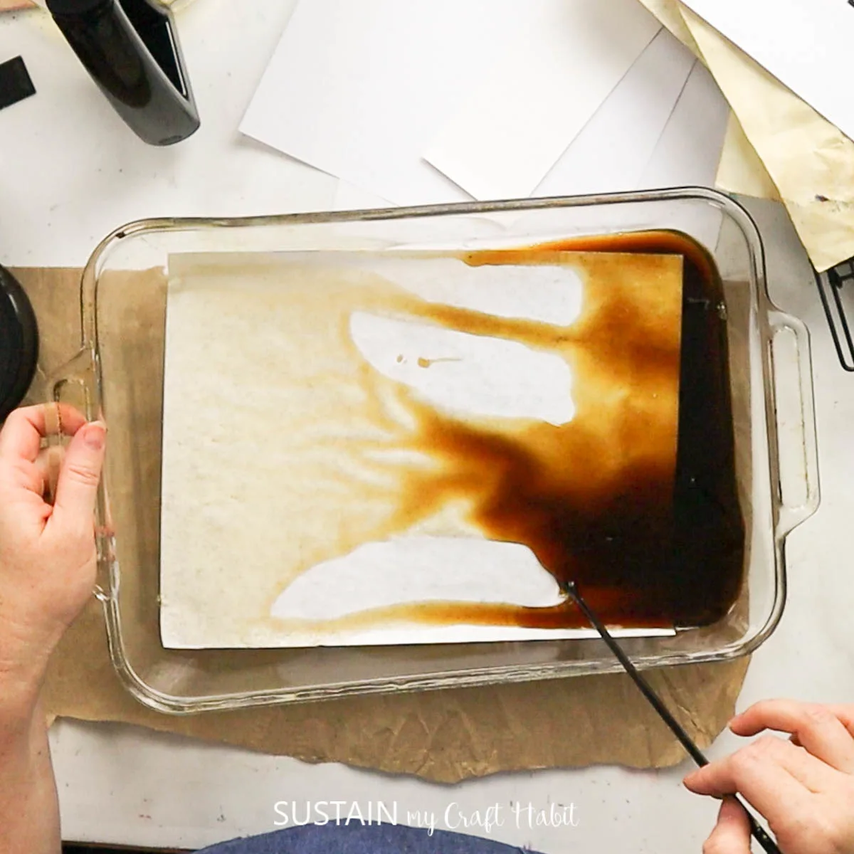placing plain paper into a shallow pan with coffee