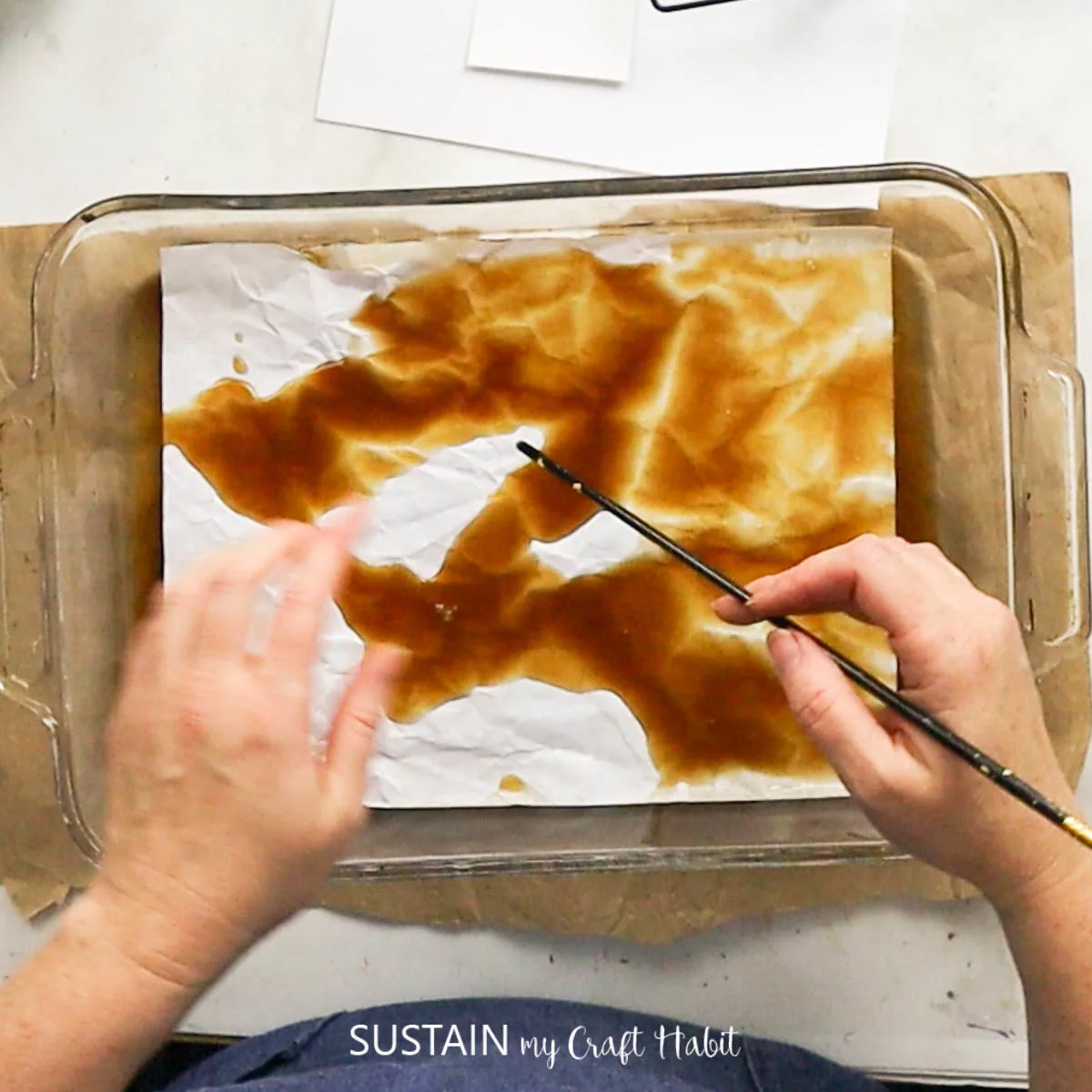 using a small paint brush to spread coffee on paper