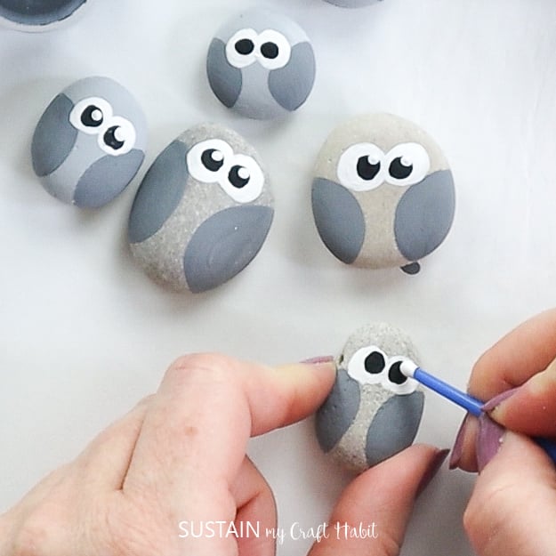 Dabbing white paint to the owl rock eyes.