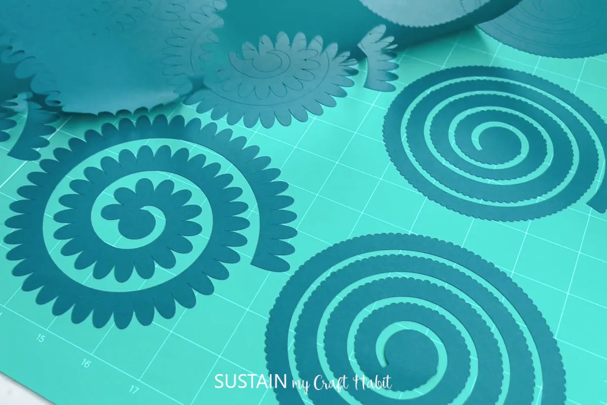 teal colored spiral shapes on a Cricut cutting mat