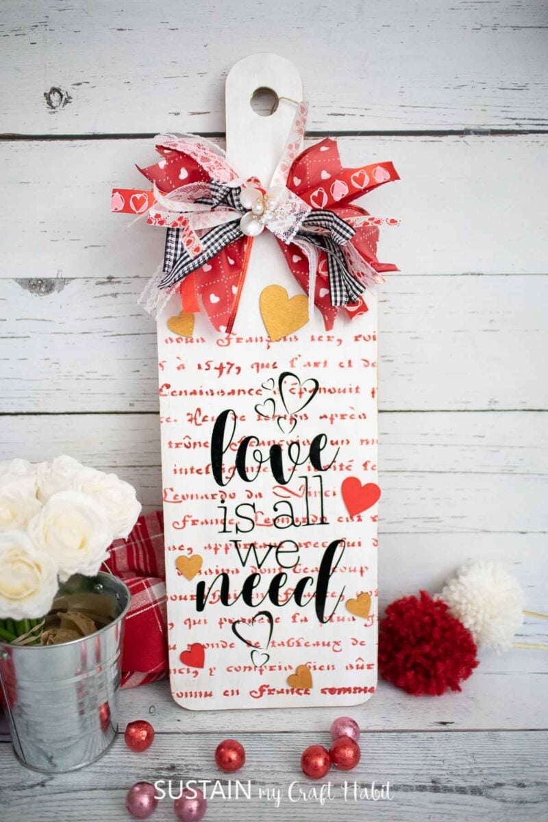 Wood panel Valentine's day sign painted and decorated with script, ribbon and a vinyl cutout.