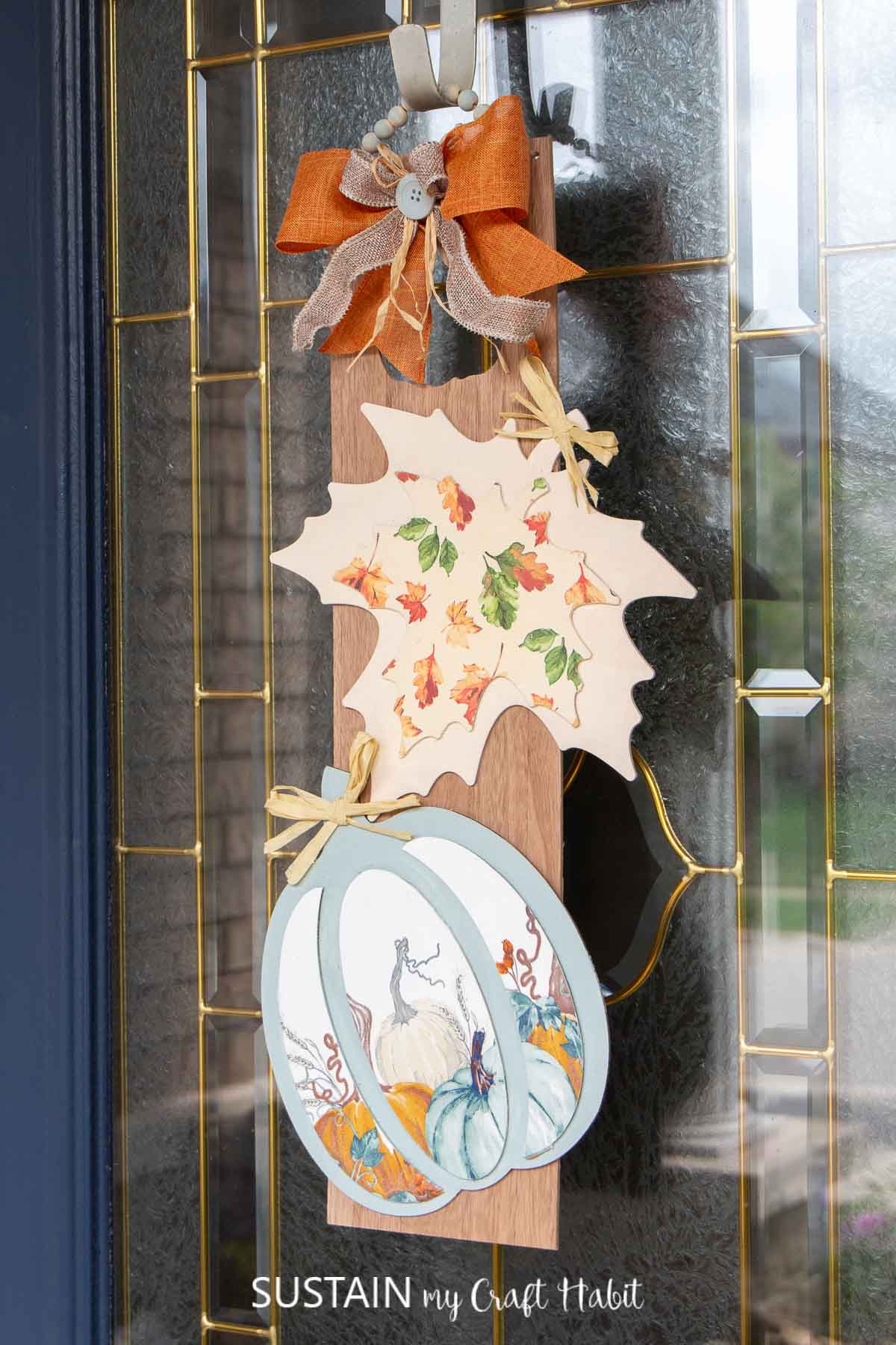Fall door hanger with a bow, wood pumpkin and wood leaf.