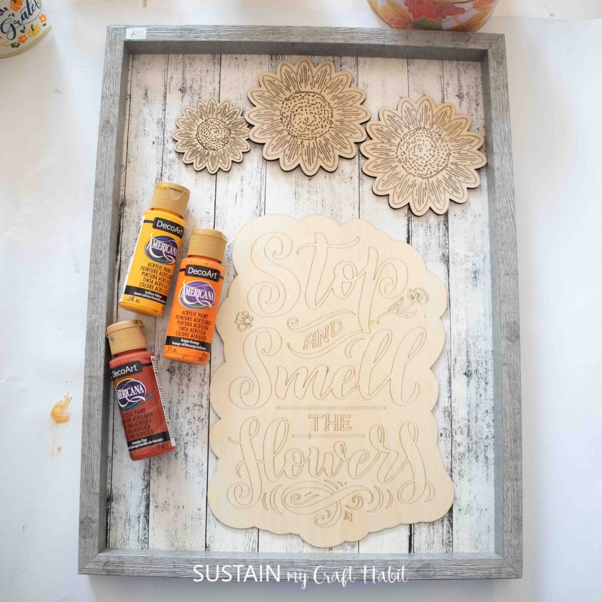 Materials needed to make a fall sign including a tray, paint, and a phrase and sunflowers cut from an xTool cutting machine.