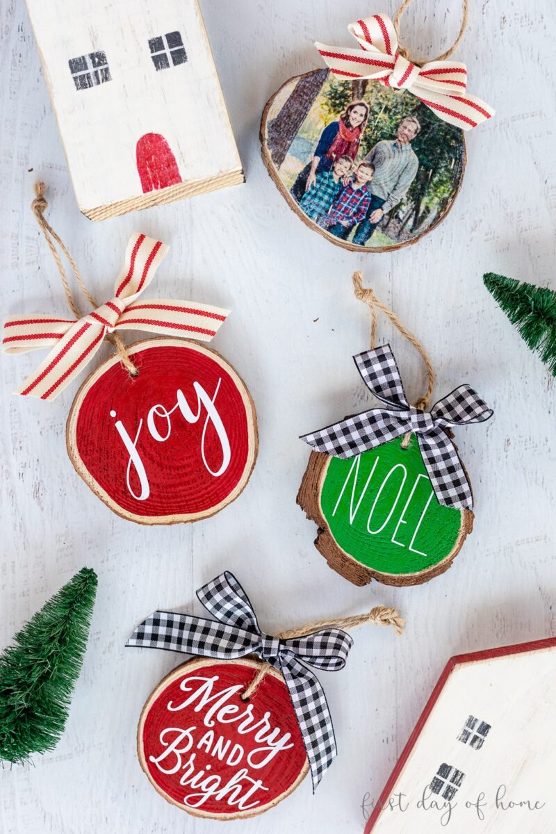 Red, green and white wood slice Christmas ornaments laying flat on a white surface.