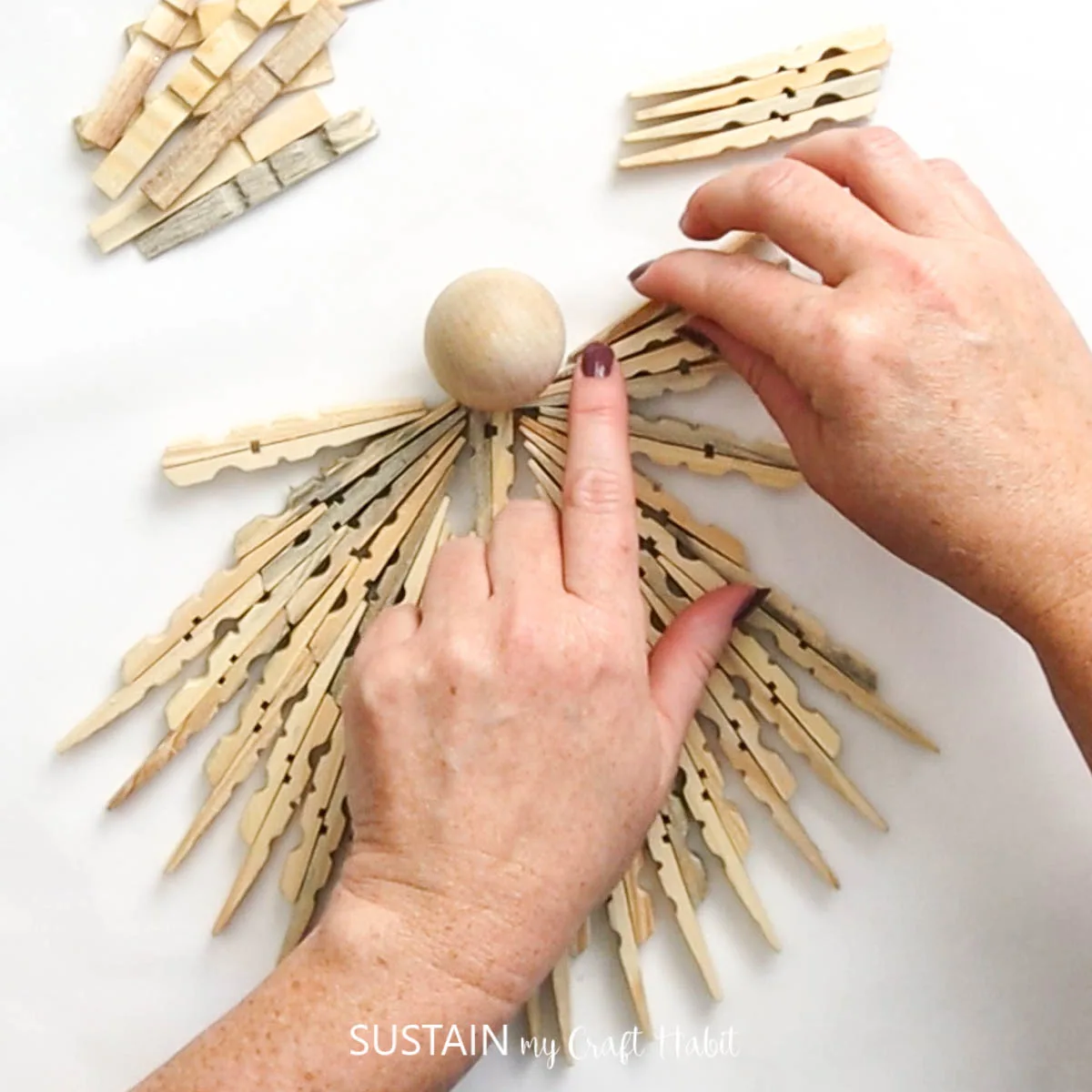 Attaching a wood  bead as a head onto the clothespin angel.