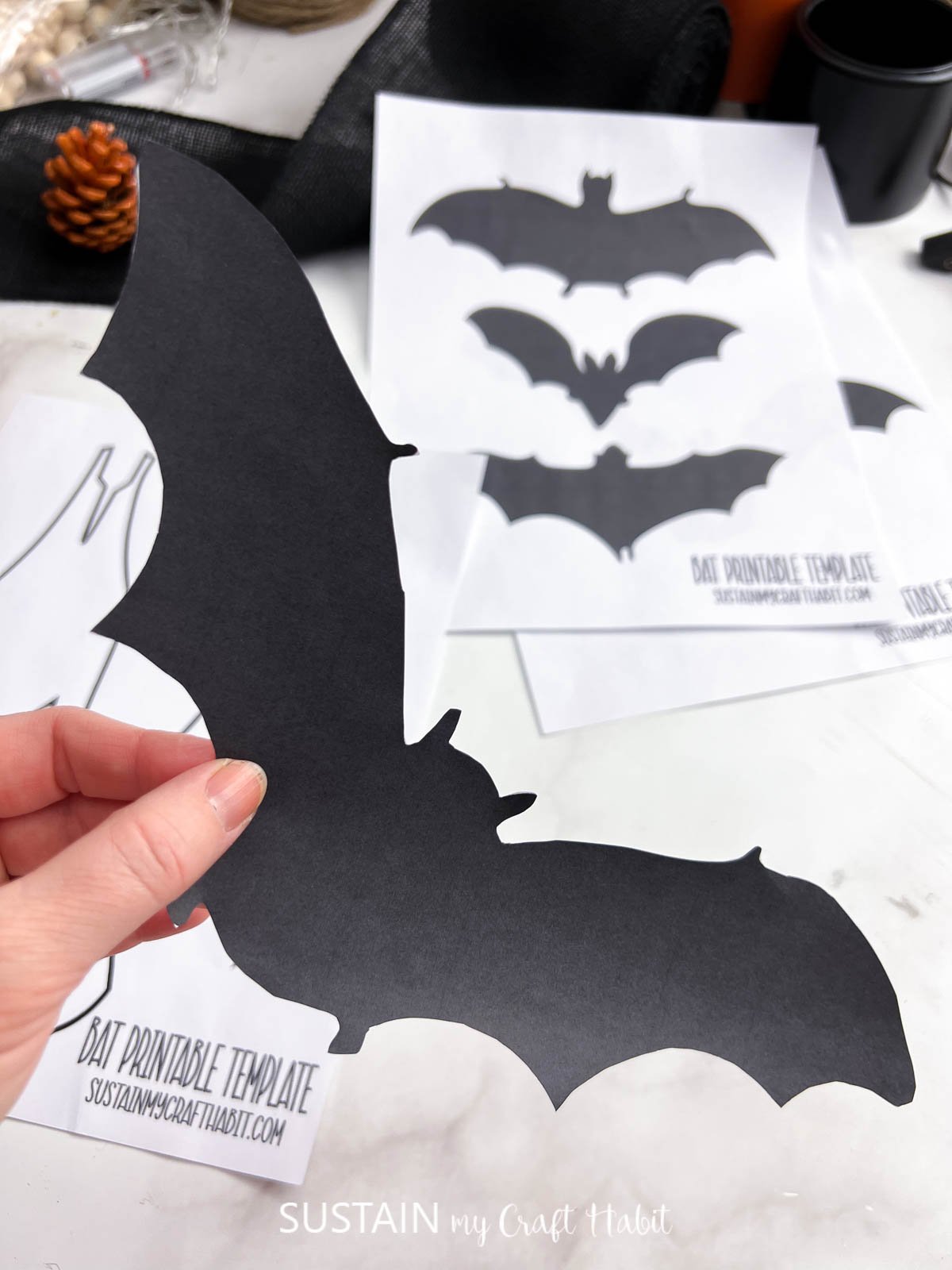 Woman's hand holding a paper bat cut out from the printable bat template.