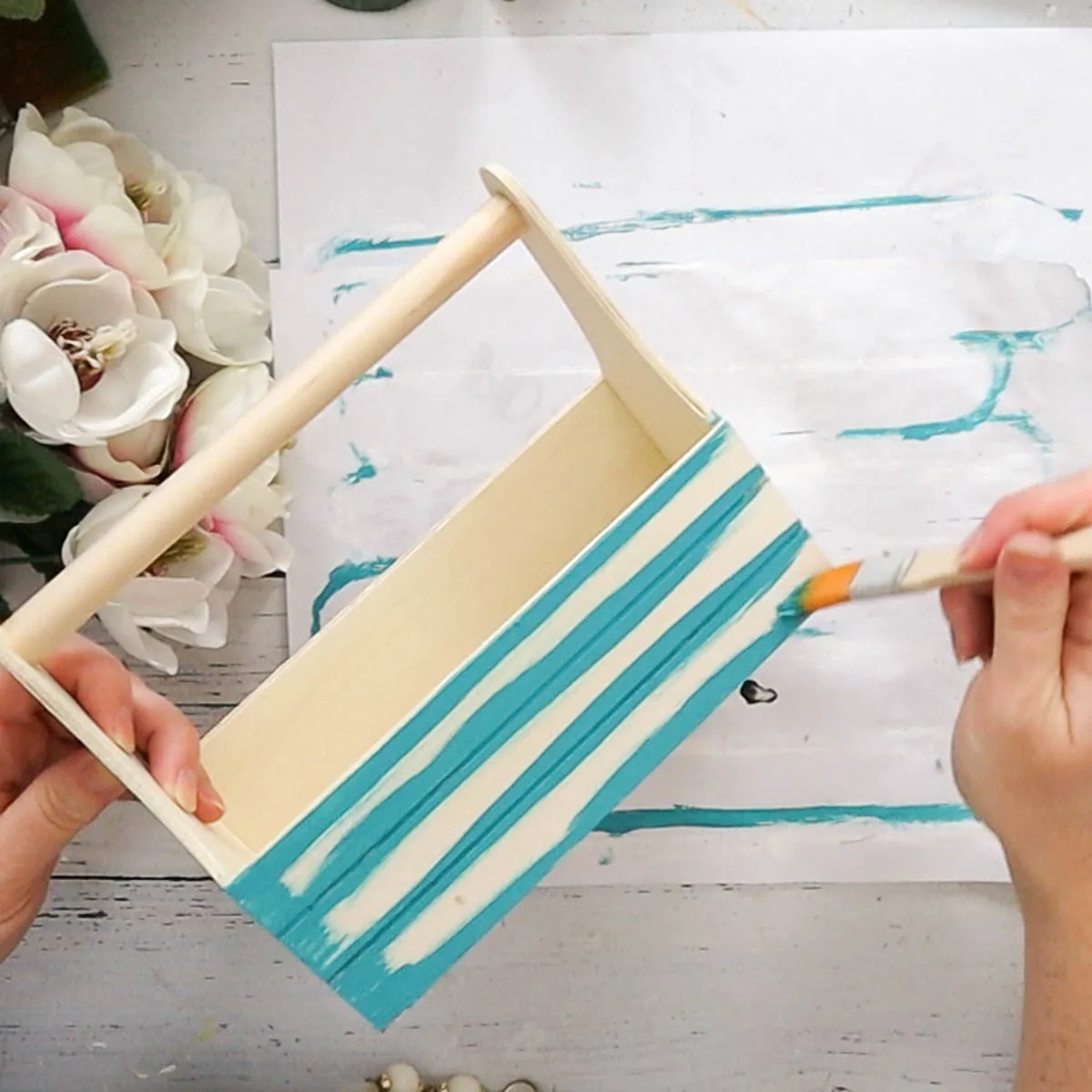 Painting a wooden caddy with blue paint.